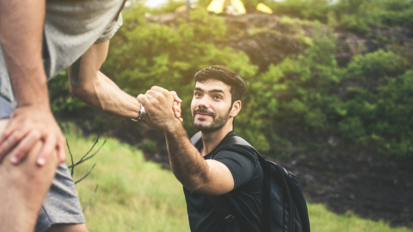 Backpackers man getting help to friend climb,Helping hand,Overcoming obstacle concept